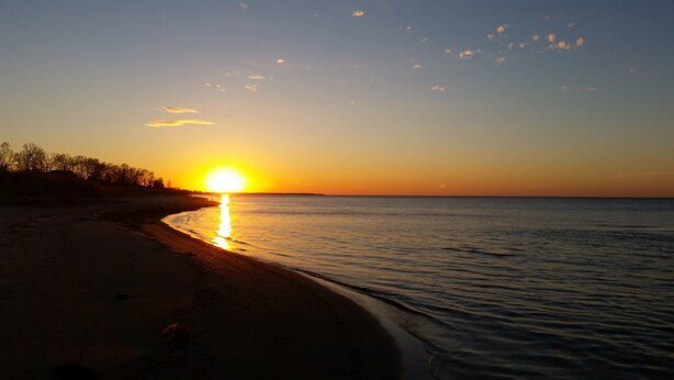 A beach at sunset with the sun reflecting on the water. - Bee 'n Bee Bed n' Breakfast (Lambton Shores)