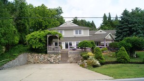A two-story house with a stone wall and a front porch. - Bee 'n Bee Bed n' Breakfast (Lambton Shores)