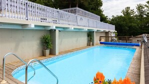A swimming pool with a wooden deck, metal pool ladder, and a white fence. - Bee 'n Bee Bed n' Breakfast (Lambton Shores)