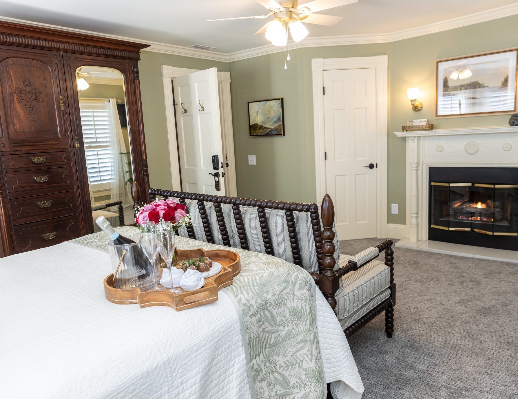 A bedroom with a bed, a wooden chair, a fireplace, and a door.