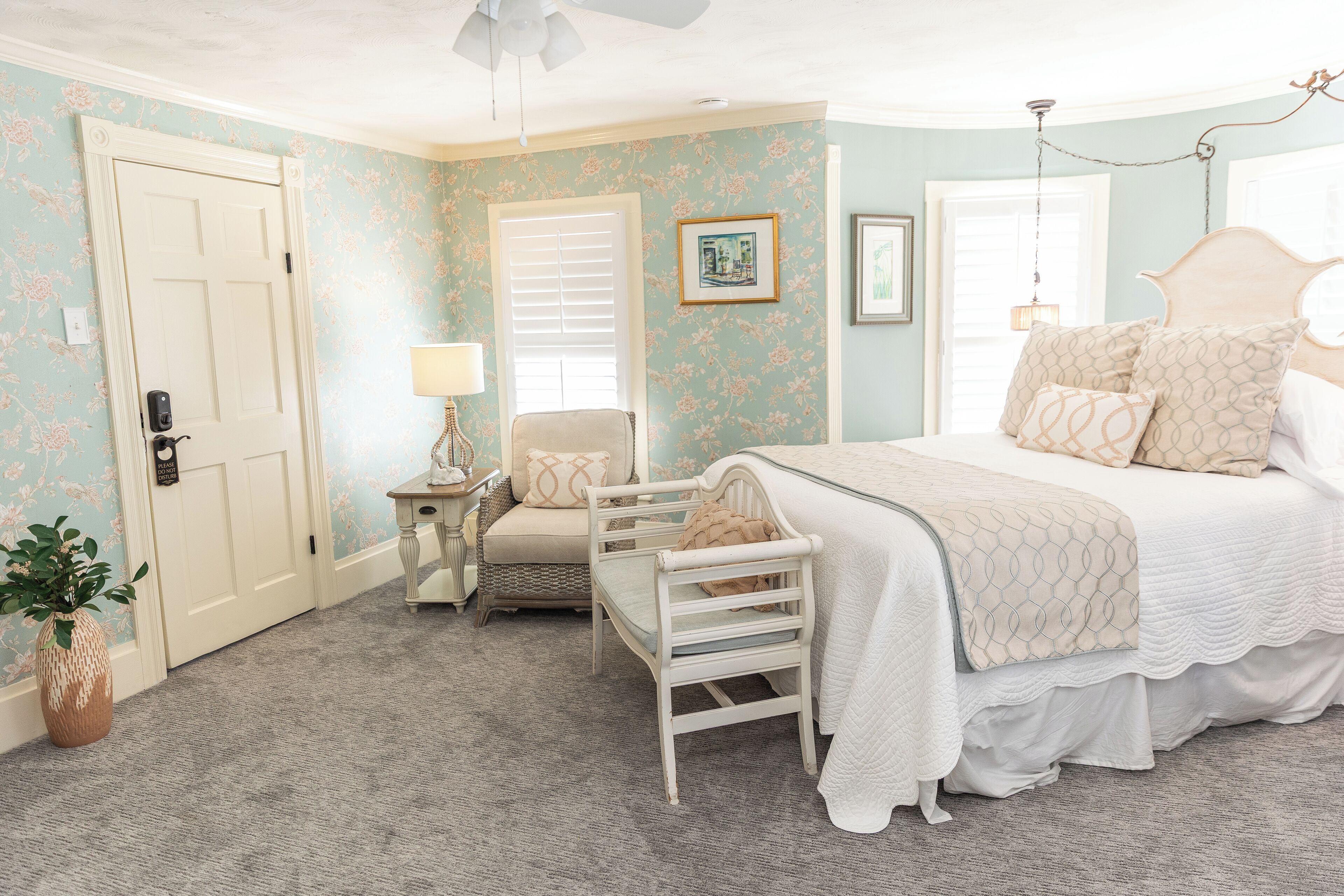 A bedroom with a bed, a chair, a lamp, and a door.