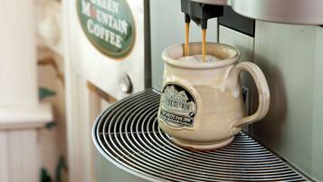 A coffee machine dispensing coffee into a mug with a label that reads "The White Doe Inn".