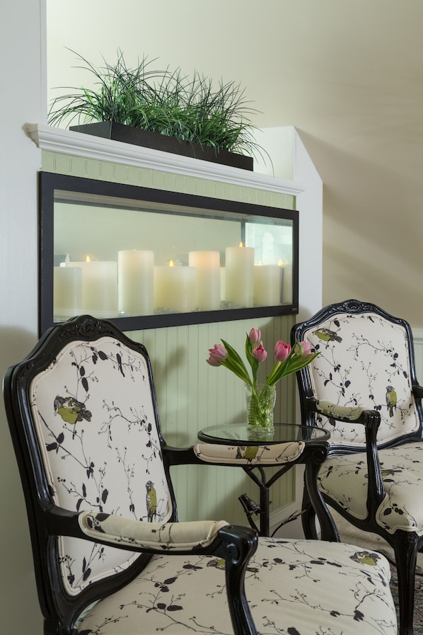 A dining area with a table and four chairs, a mirror, and a row of candles. - White Doe Inn (Manteo)