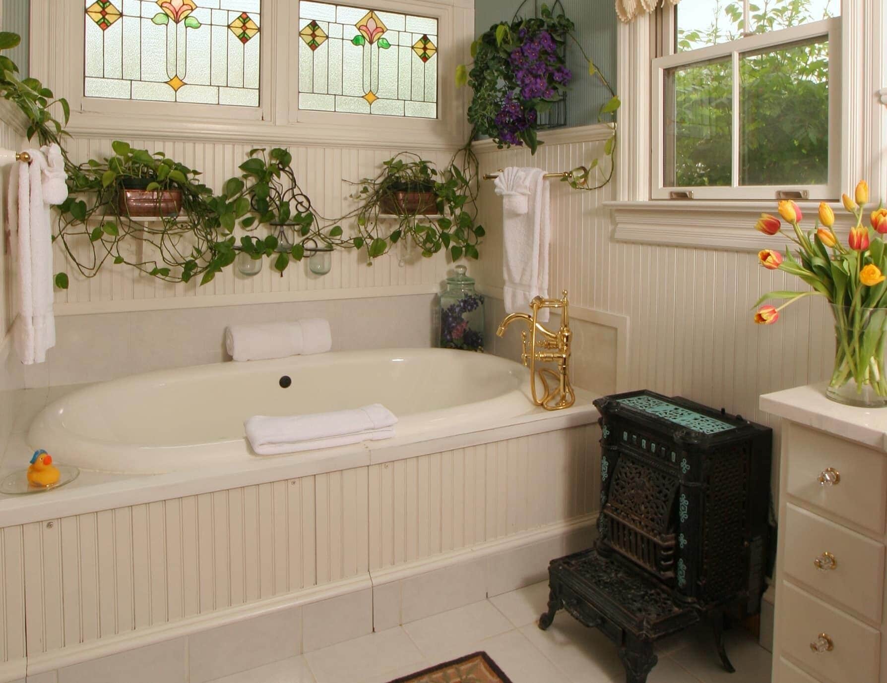 Une salle de bain avec une baignoire, un lavabo de style r étro et une fenêtre ornée de vitraux.