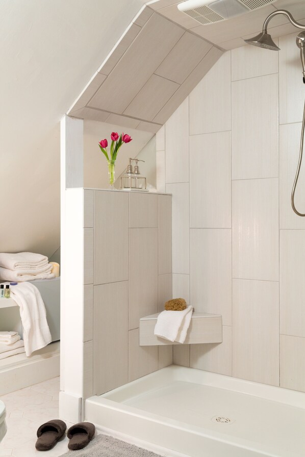 A modern bathroom with a bathtub, a shower, and a vanity with a towel rack.