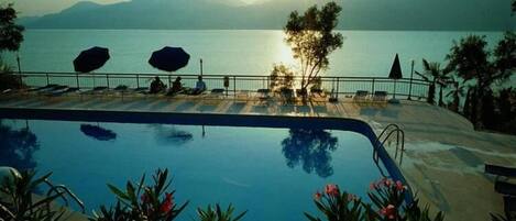 Una piscina al aire libre de temporada, sombrillas