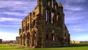 A large, historic stone building with multiple arches and towers, surrounded by a grassy area. - Glenora Guest House (Whitby)
