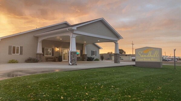 A motel with a covered entrance, a signboard, and a grassy area in front.