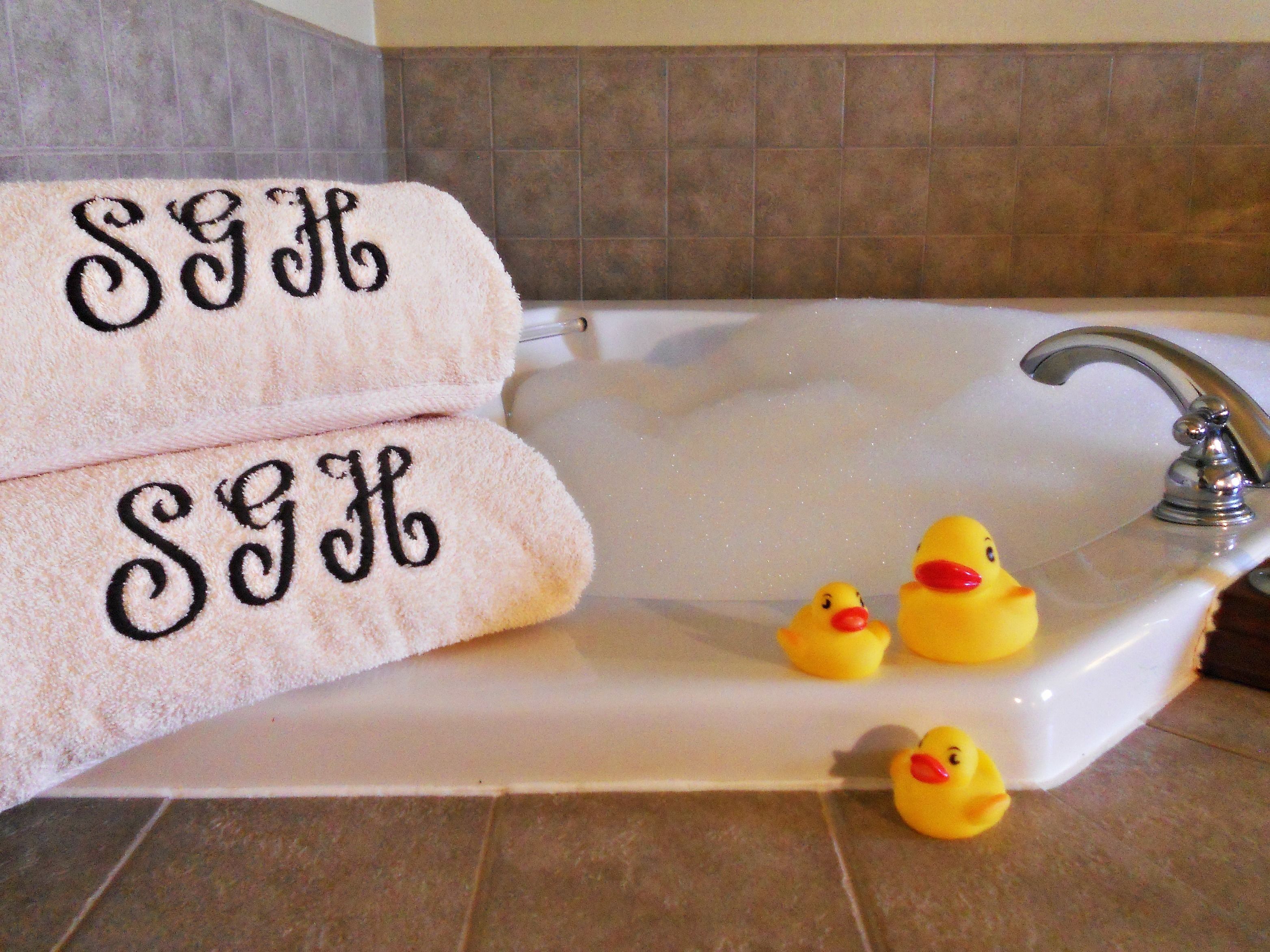 Una bañera con dos toallas y tres patitos de goma.