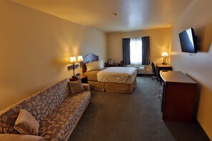 A hotel room with a sofa, two beds, a desk, and a TV.