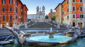 A historic fountain with ornate sculptures, surrounded by classical architecture and a prominent church in the background. - Chic & Town Luxury Rooms Piazza del popolo (Rome)