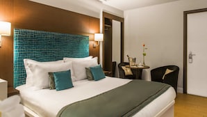 A hotel room with a large bed, a headboard with a blue pattern, a small table with a vase, and a chair. - Chic & Town Luxury Rooms Piazza del popolo (Rome)