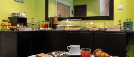 Une table mise pour le petit-déjeuner, avec une nappe pour deux personnes, comprenant des assiettes avec des toasts, une omelette, un croissant, une tasse de café et un verre de jus de fruits.