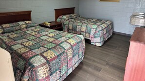 A room with two beds, each with a patterned quilt, a wooden nightstand with a telephone, and framed artwork on the walls. - Interstate Inn Express (Tulsa)