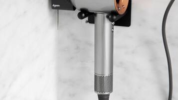 Un secador de pelo Dyson montado en la pared con un cable.