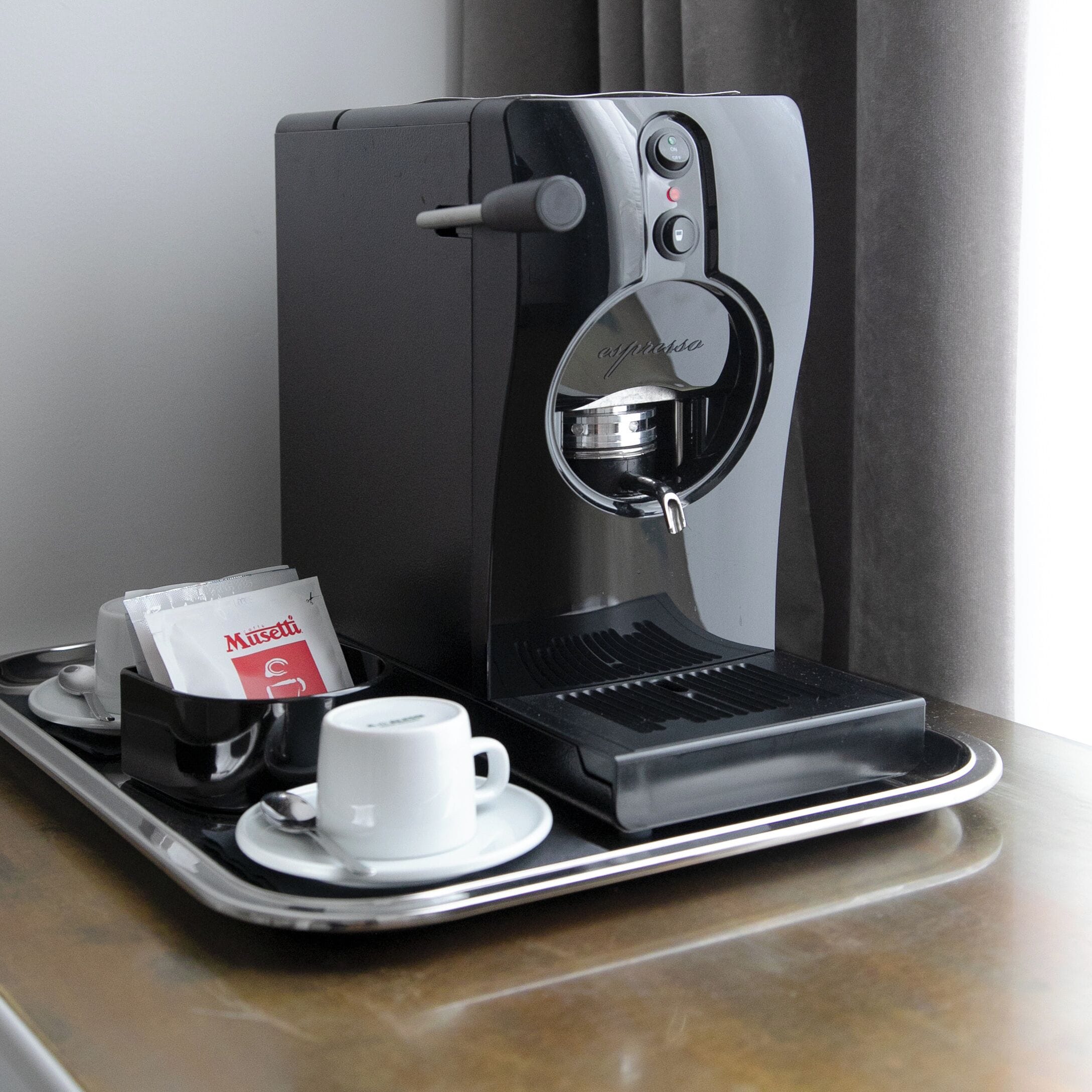 Una macchina del caffè con una tazza e una confezione di caffè su un vassoio.