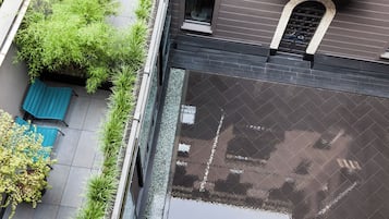 Ein Blick von oben auf einen Innenhof mit Pool, Grünpflanzen und einer blauen Bank.