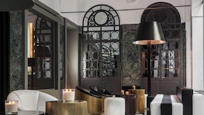 A modern lobby with a seating area, a large black lamp, and decorative candles. - Senato Hotel Milano (Milan)