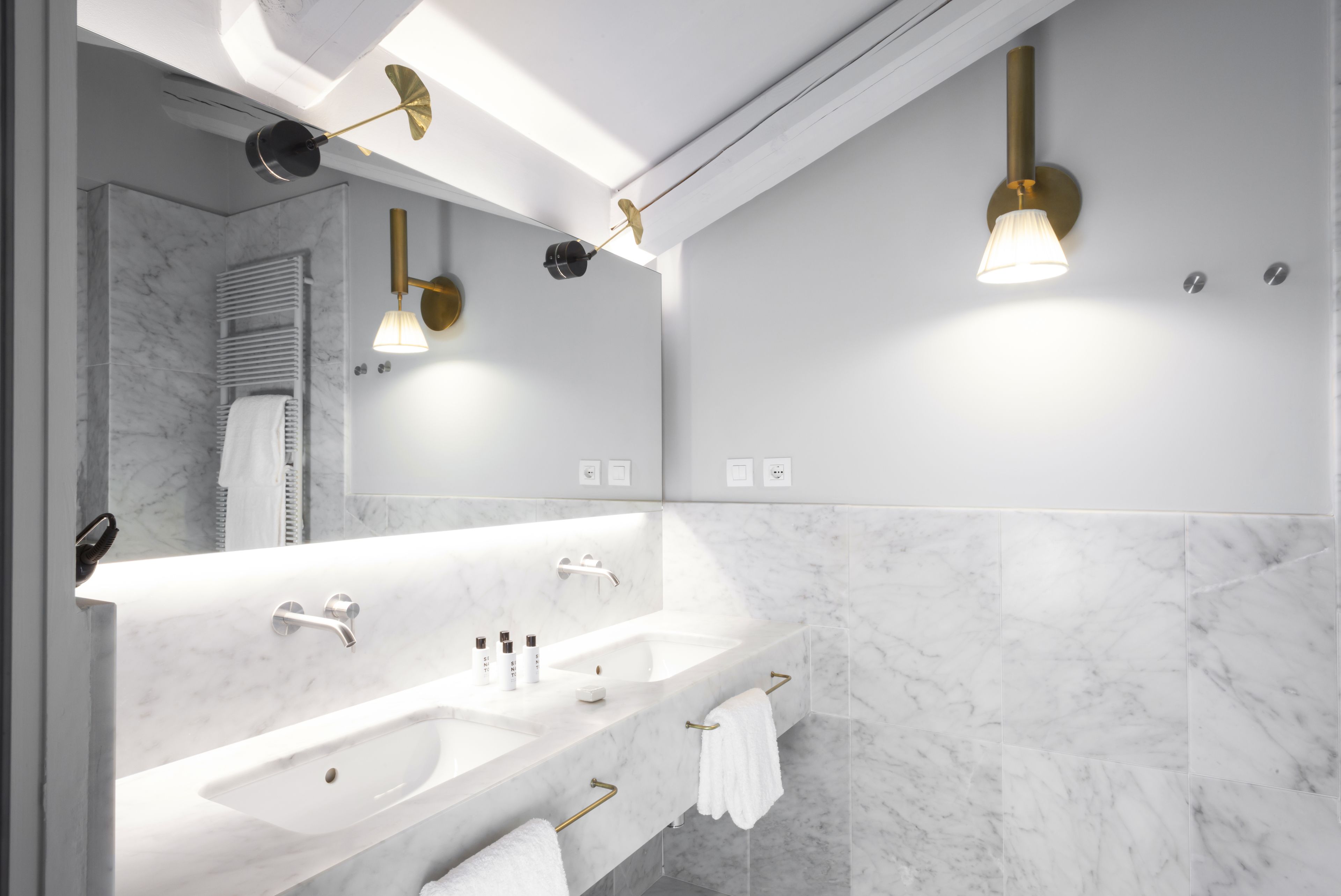 A modern bathroom with a large mirror, two sinks, and a towel rack.