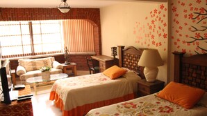 Una habitación con dos camas, un escritorio, una silla y una televisión.
