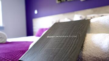 A room with a bed, a purple wall, and a sign labeled "GUEST INFORMATION".
