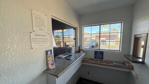 Ein Empfangsbereich mit Theke, einem Fenster mit Ausblick und Hinweisschildern an der Wand.