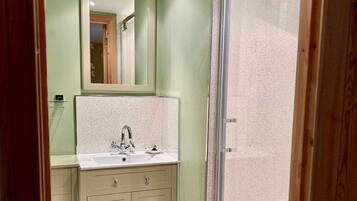 A bathroom with a shower, a sink, and a mirror.