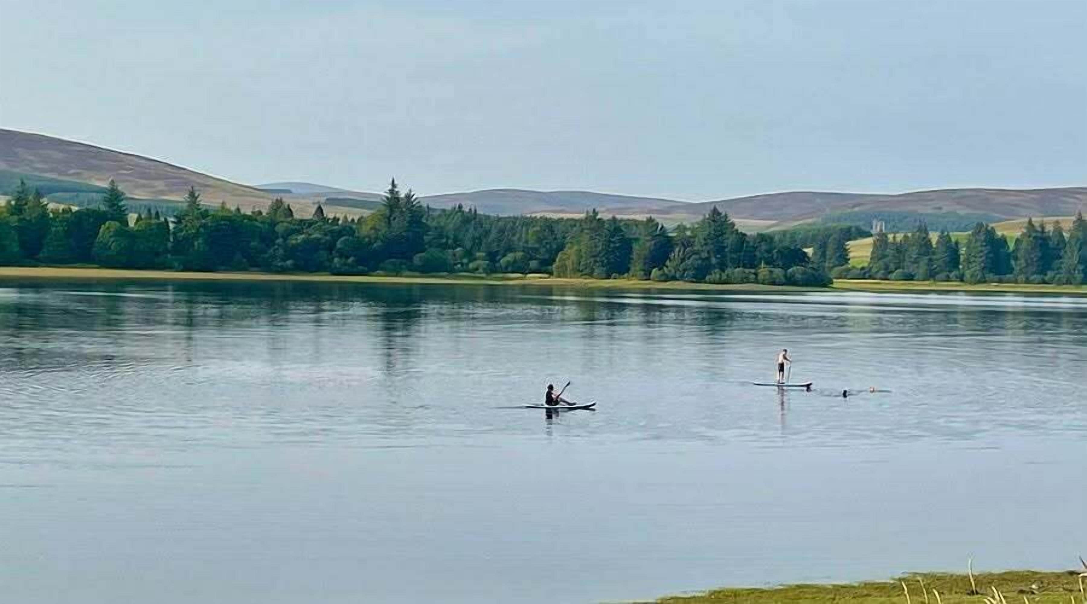 Un llac tranquil amb dues persones fent caiac.