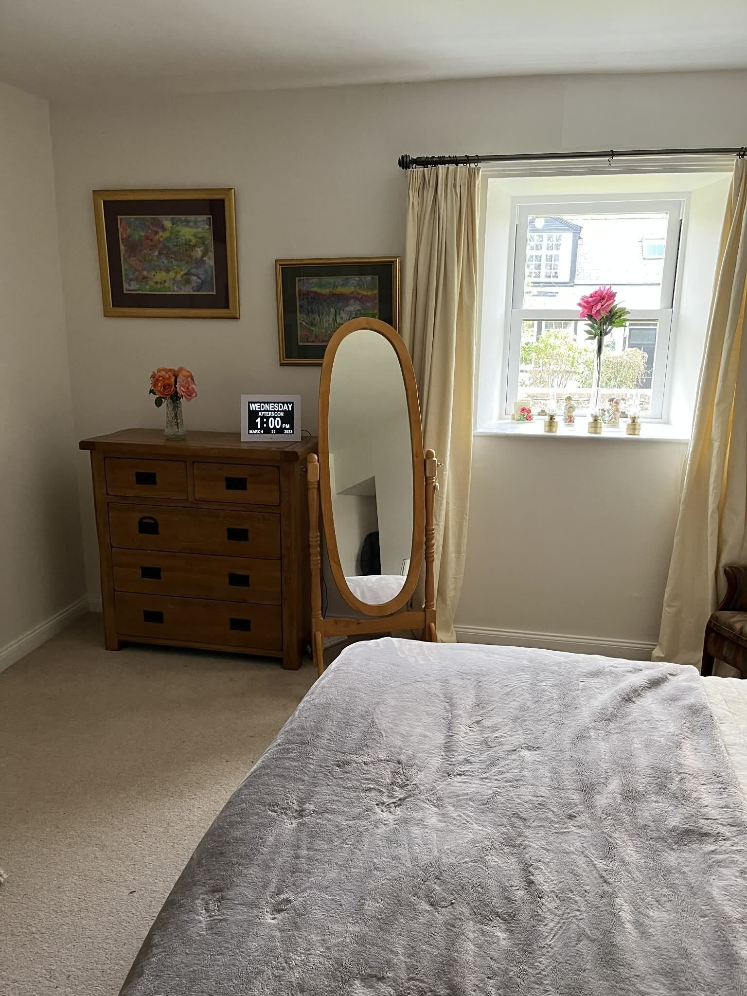 Un dormitorio con cama, cómoda, espejo y ventana con cortinas.