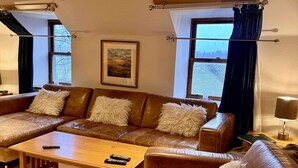 A living room with a brown leather sofa set, a wooden coffee table, and a framed picture on the wall. - Lodge at Lochside (Kirriemuir)