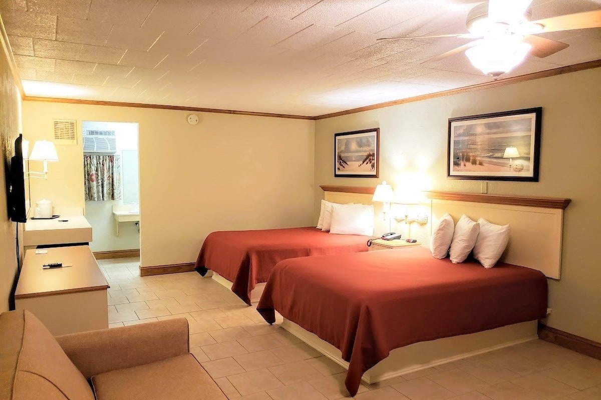 Une chambre d’hôtel avec deux lits, un bureau, une chaise et un téléviseur.
