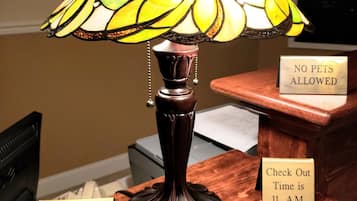 A lobby area with a stained glass lamp, a 'No Pets Allowed' sign, a 'Thank You for Not Smoking' sign, and a 'Check Out Time is 11 A.M.' sign.