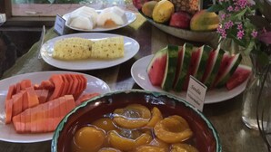 Una mesa con diversas frutas y un bol de melocotones en rodajas.