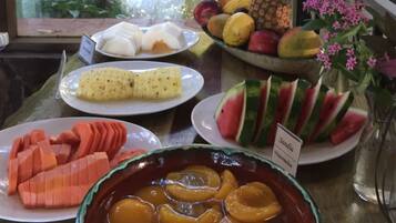 Una mesa con diversas frutas y un bol de melocotones en rodajas.