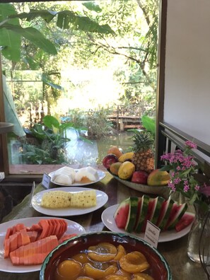 A table with various fruits and a bowl of sliced peaches. - El Pueblito Iguazu (Puerto Iguazú)
