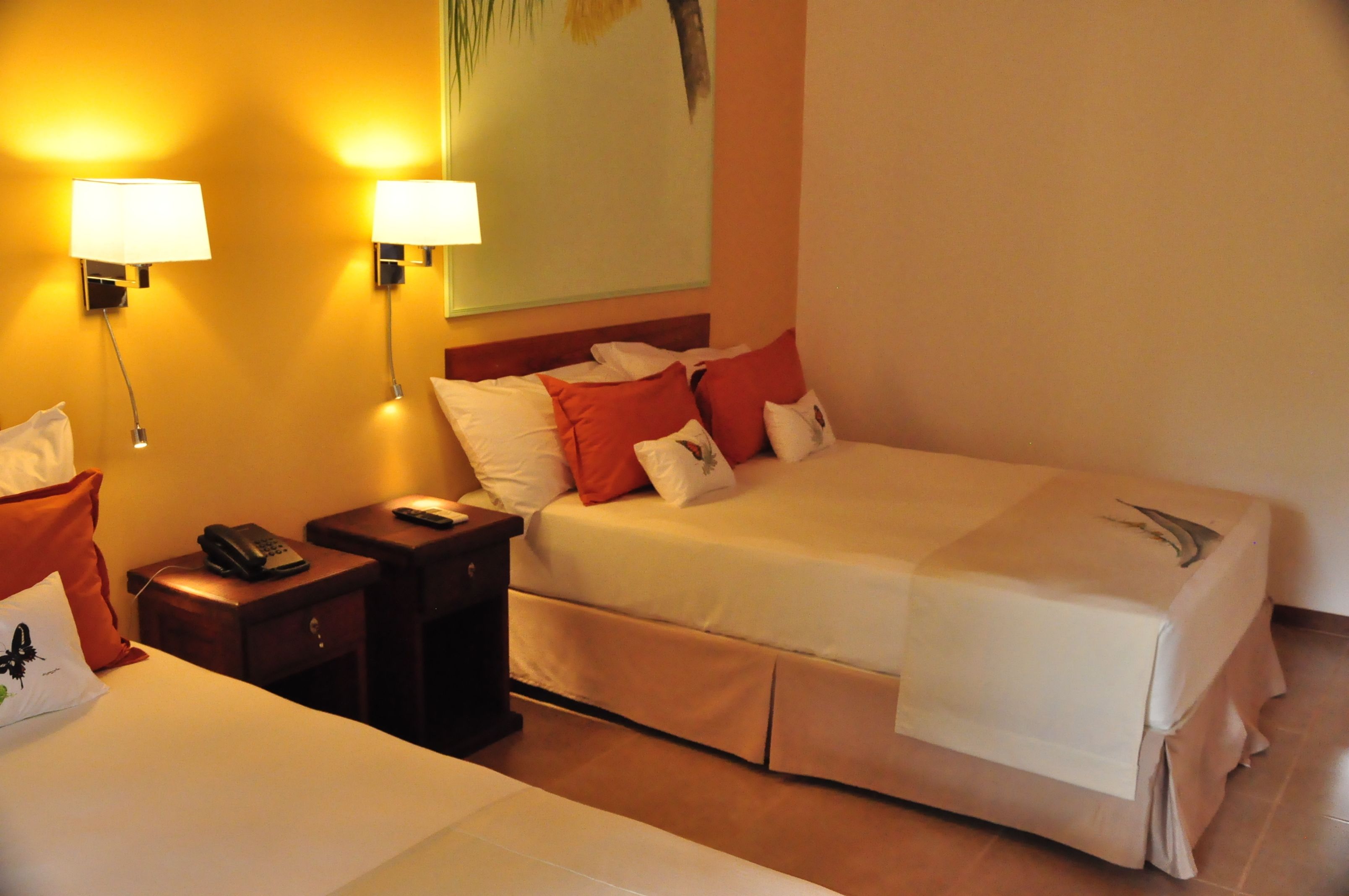 Habitación de hotel con dos camas, una mesita de noche con teléfono y lámparas de pared.