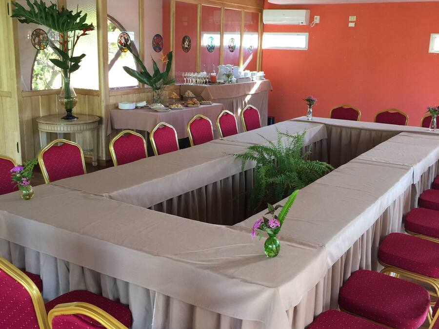 Un salón de conferencias con una larga mesa, sillas tapizadas en rojo y una lámpara de araña.