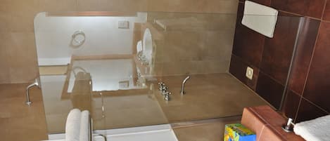 Un baño con bañera vidriada, lavamanos blanco y un perchero para toallas.