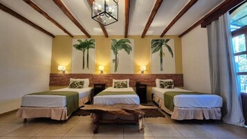 Una habitación con tres camas, una mesa de centro de madera y lámparas fijadas a la pared.
