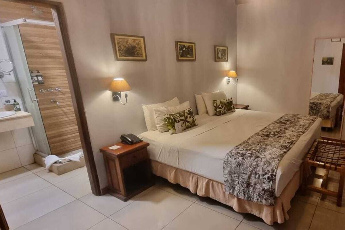 A bedroom with a bed, bedside lamps, a desk, and a mirror.