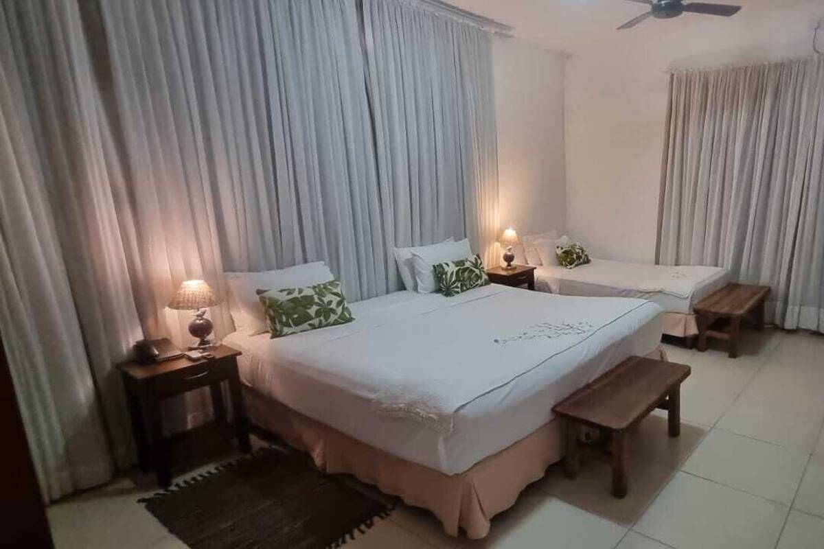 A hotel room with two beds, a ceiling fan, and a TV mounted on the wall.