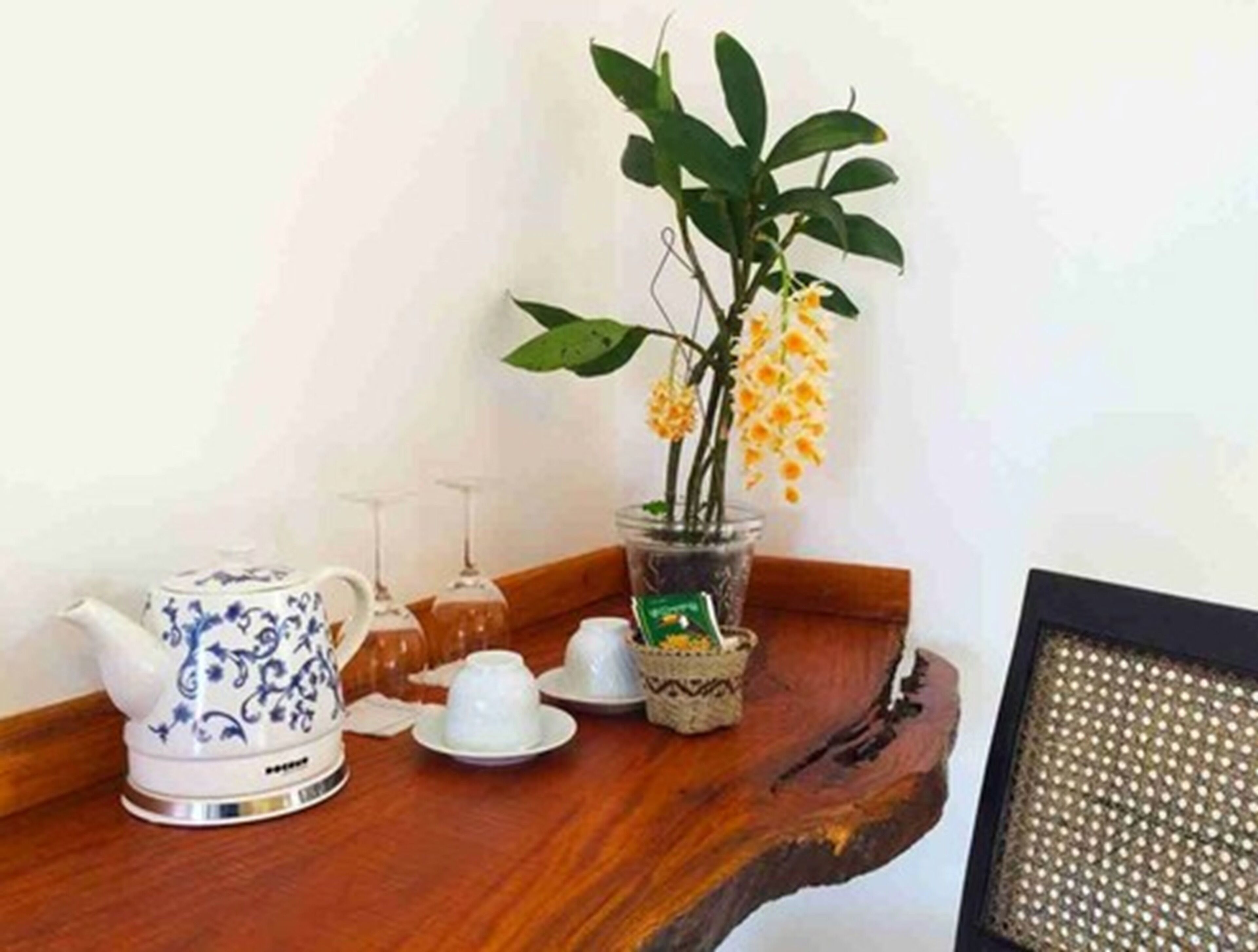 A wooden tray with a teapot, cups, and a vase with flowers.