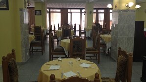 Un'area pranzo con tavoli rotondi, sedie e un lampadario.
