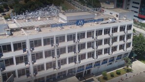 Un edificio a più piani con un cartello che riporta "HOTEL AEROPORT" e testo in arabo. Presenta uno stile architettonico moderno, con tetto piatto e numerosi balconi.
