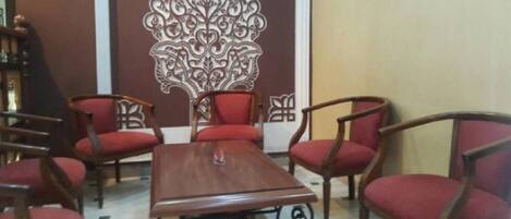 Un salón de conferencias con una mesa de madera y seis sillas tapizadas rojas.