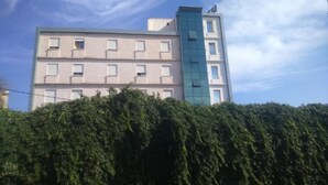 A multi-story building with a flat facade, several windows, and a section with a blue glass exterior. - Hotel Roza (Algiers)