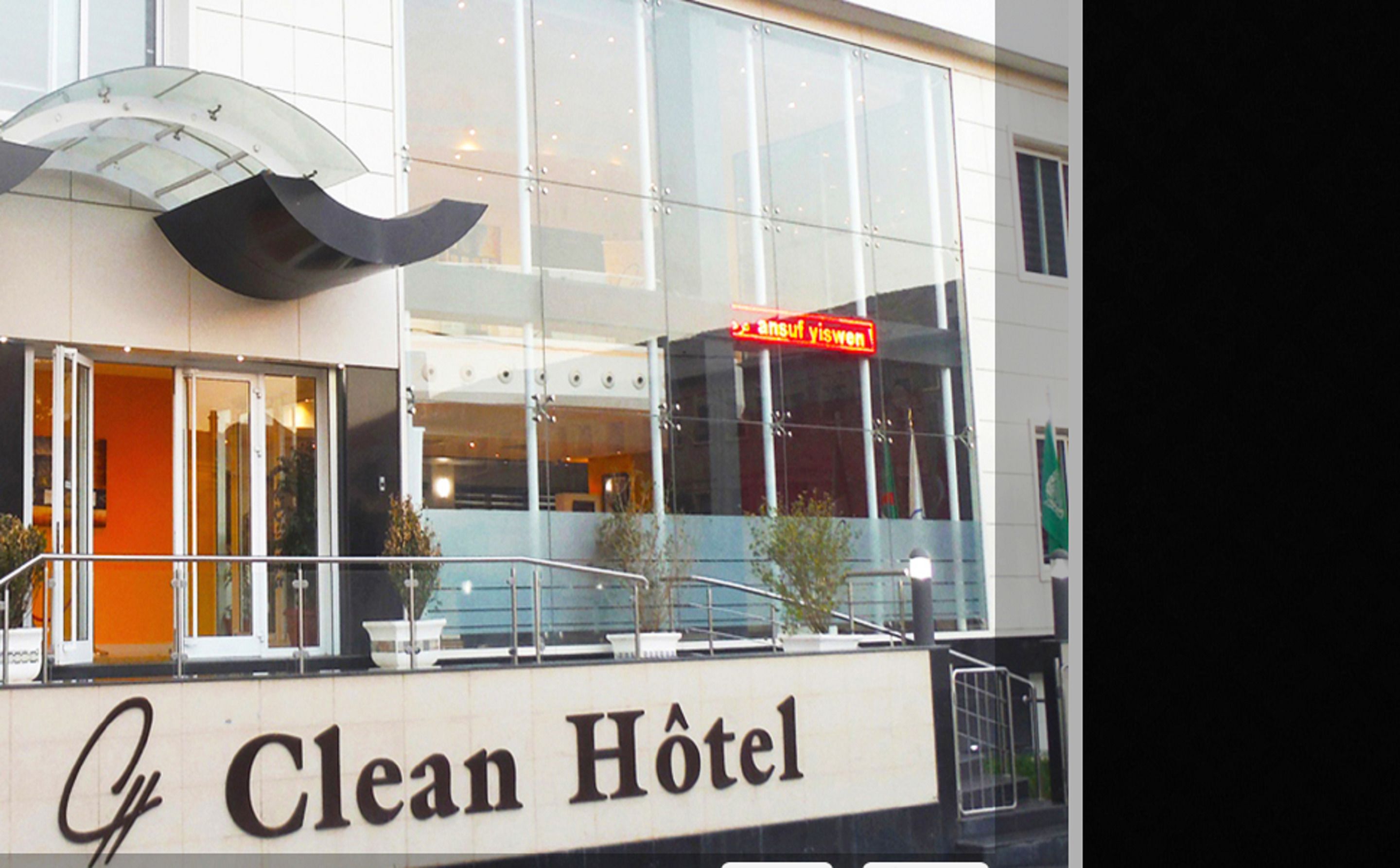 A hotel with a glass facade, a sign reading "Clean Hotel," and a red sign above the entrance.