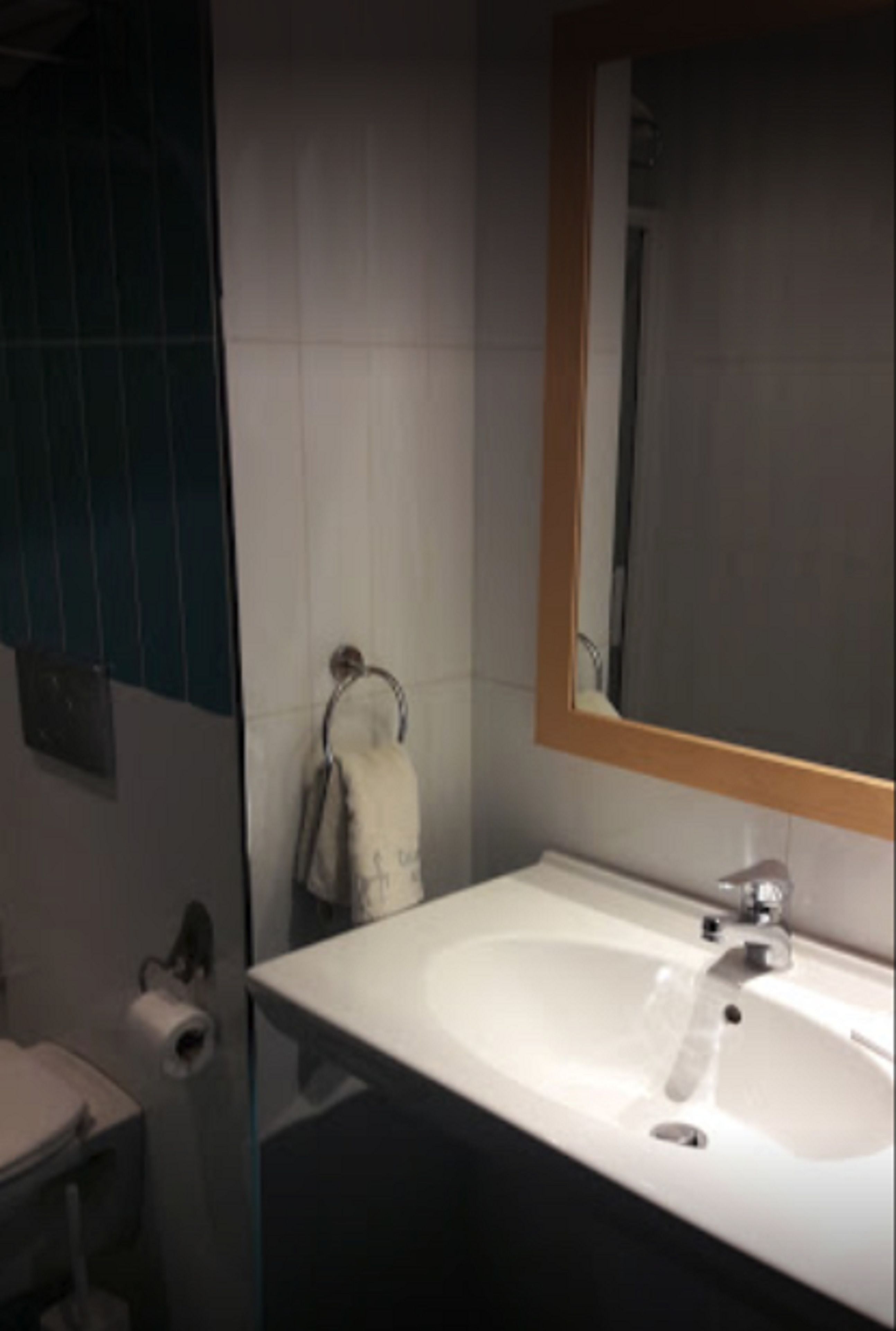 Une salle de bain avec un lavabo blanc, un miroir et une serviette suspendue à un porte-serviettes.
