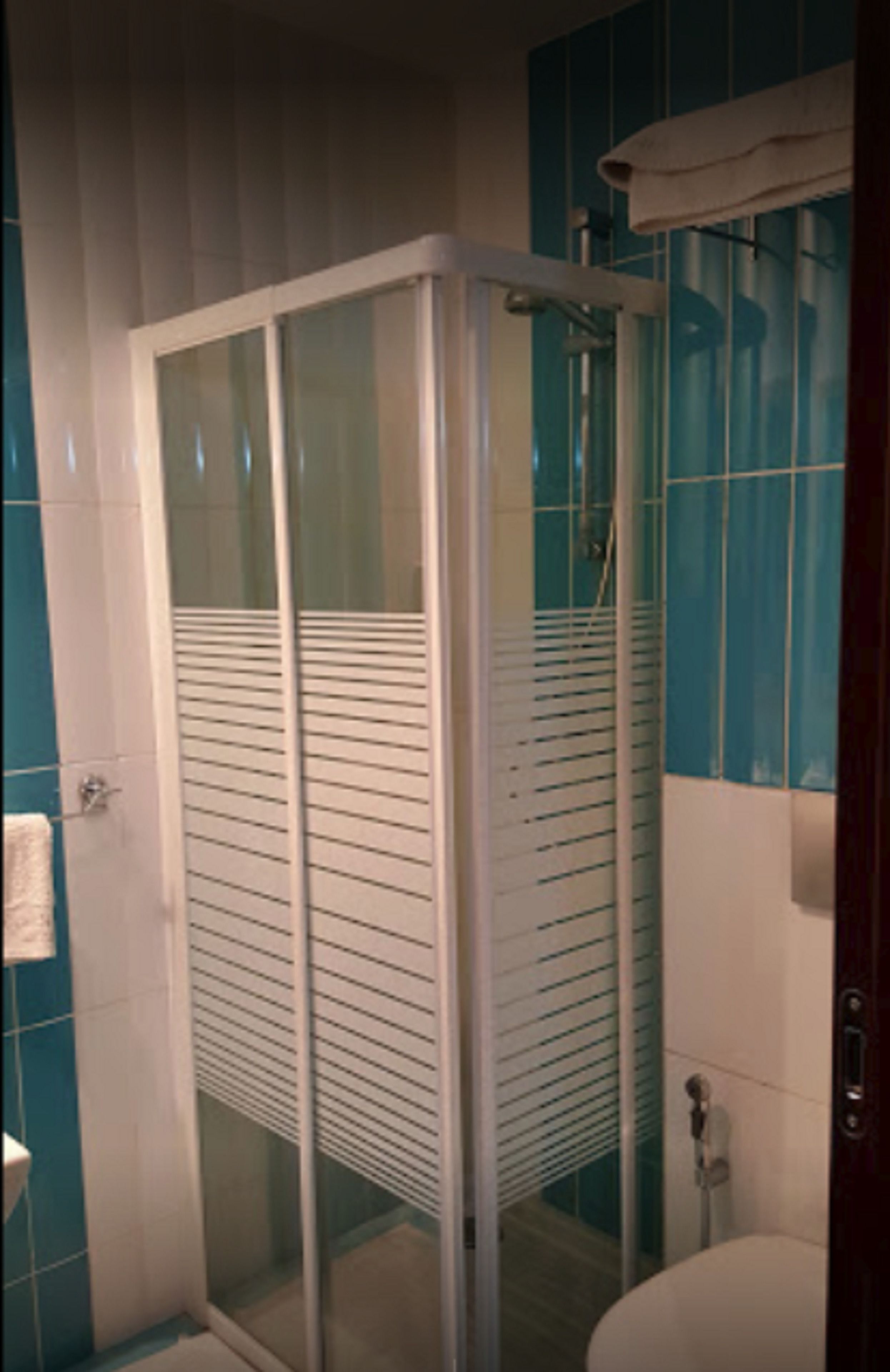 Un baño con ducha de vidrio, un lavamanos blanco y azulejos azules.
