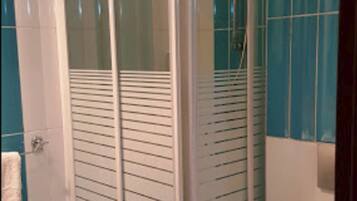 Un baño con ducha de vidrio, un lavamanos blanco y azulejos azules.